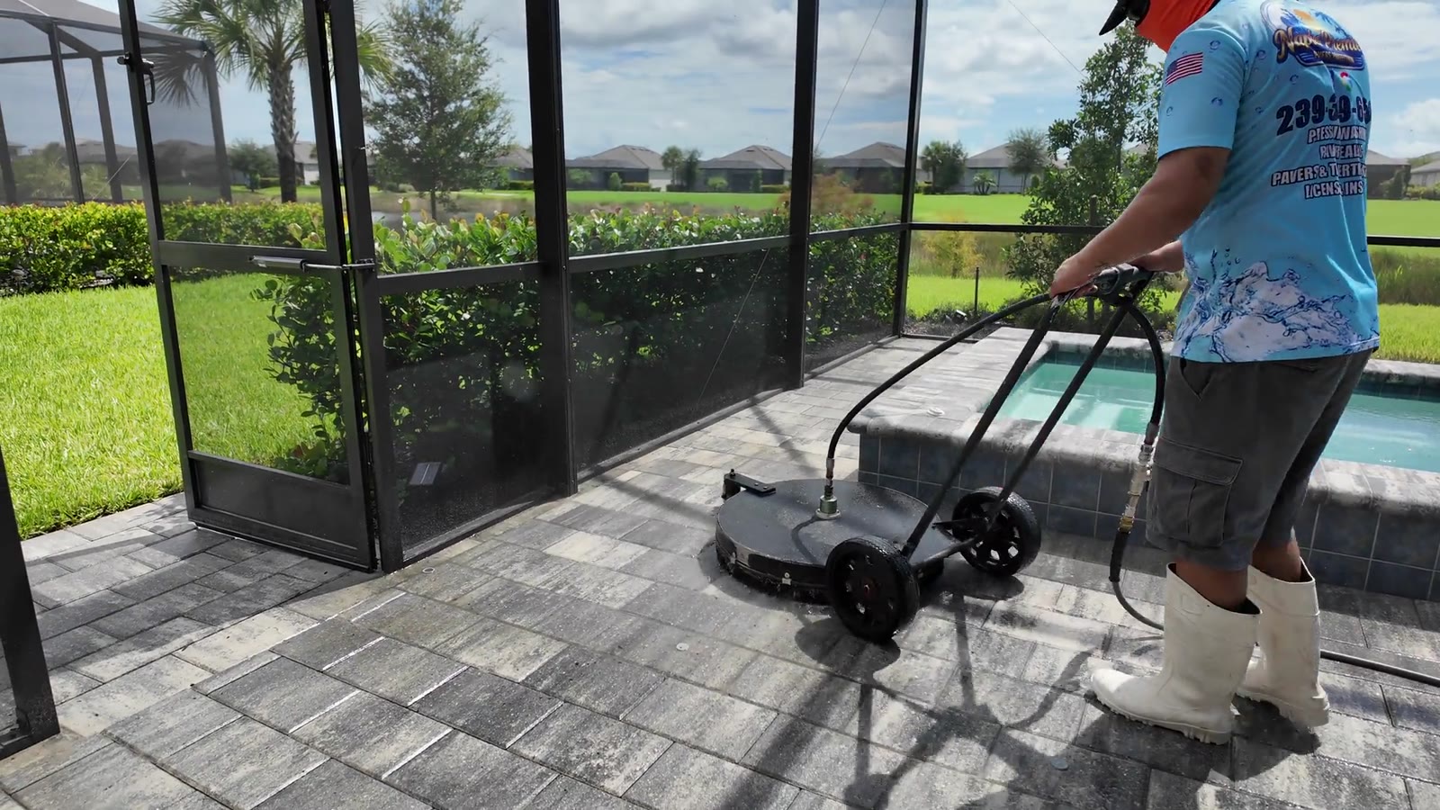 A crew member running a surface cleaner across a paver pool deck