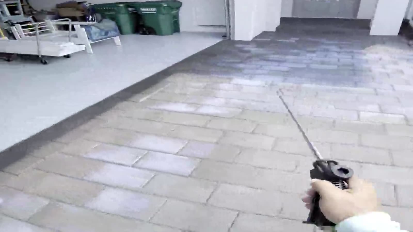 A sealer wand spraying across a paver driveway